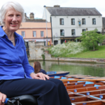 Sarah Stones, Motivation Specialist, smiling beside the river,. showing a calm and relaxing space to illustrate the article about lack of motivation.